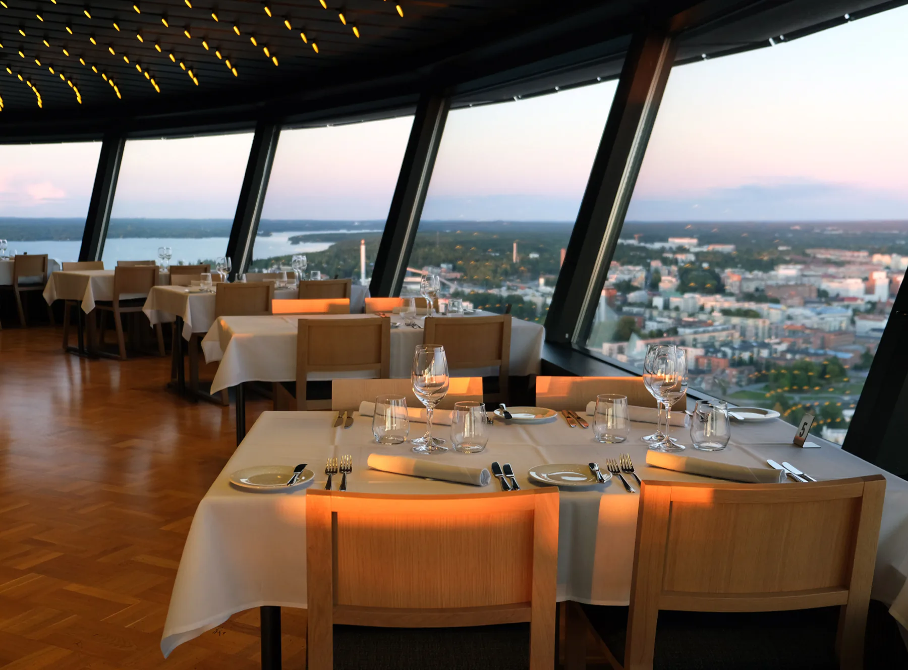 Gedeckte Tische vor großen Panoramafenstern über der Stadt