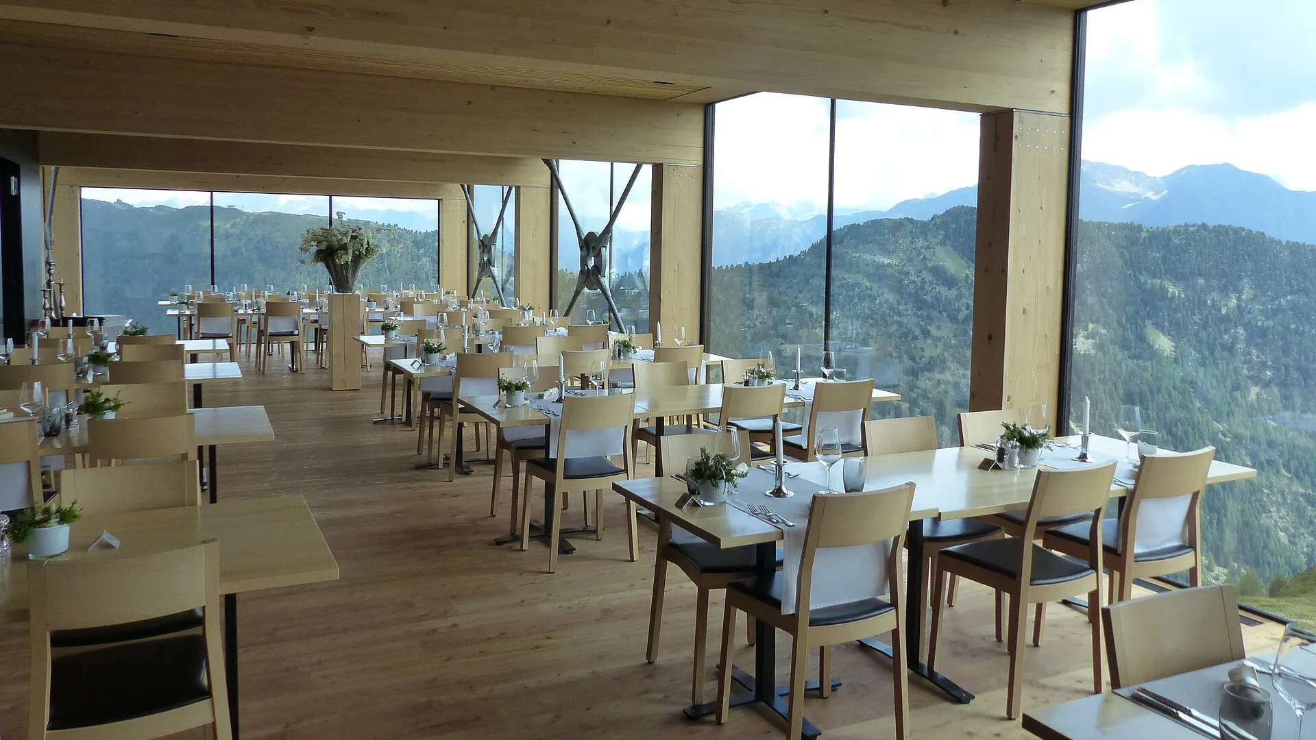 Comedor de un hotel de montaña con mesas puestas y ventanas panorámicas