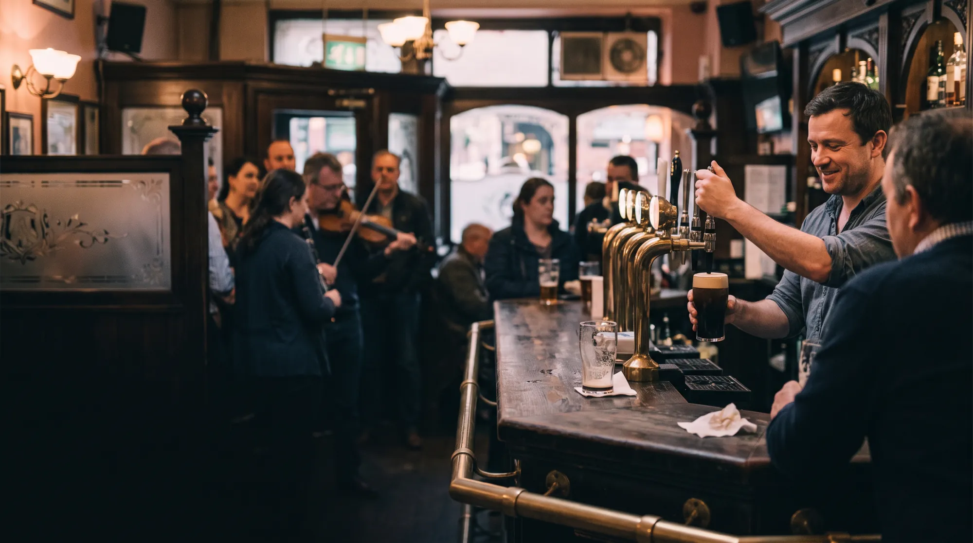 Pub tradicional con barra de madera oscura: el camarero tira una stout, al fondo unos músicos tocan el violín ante los clientes